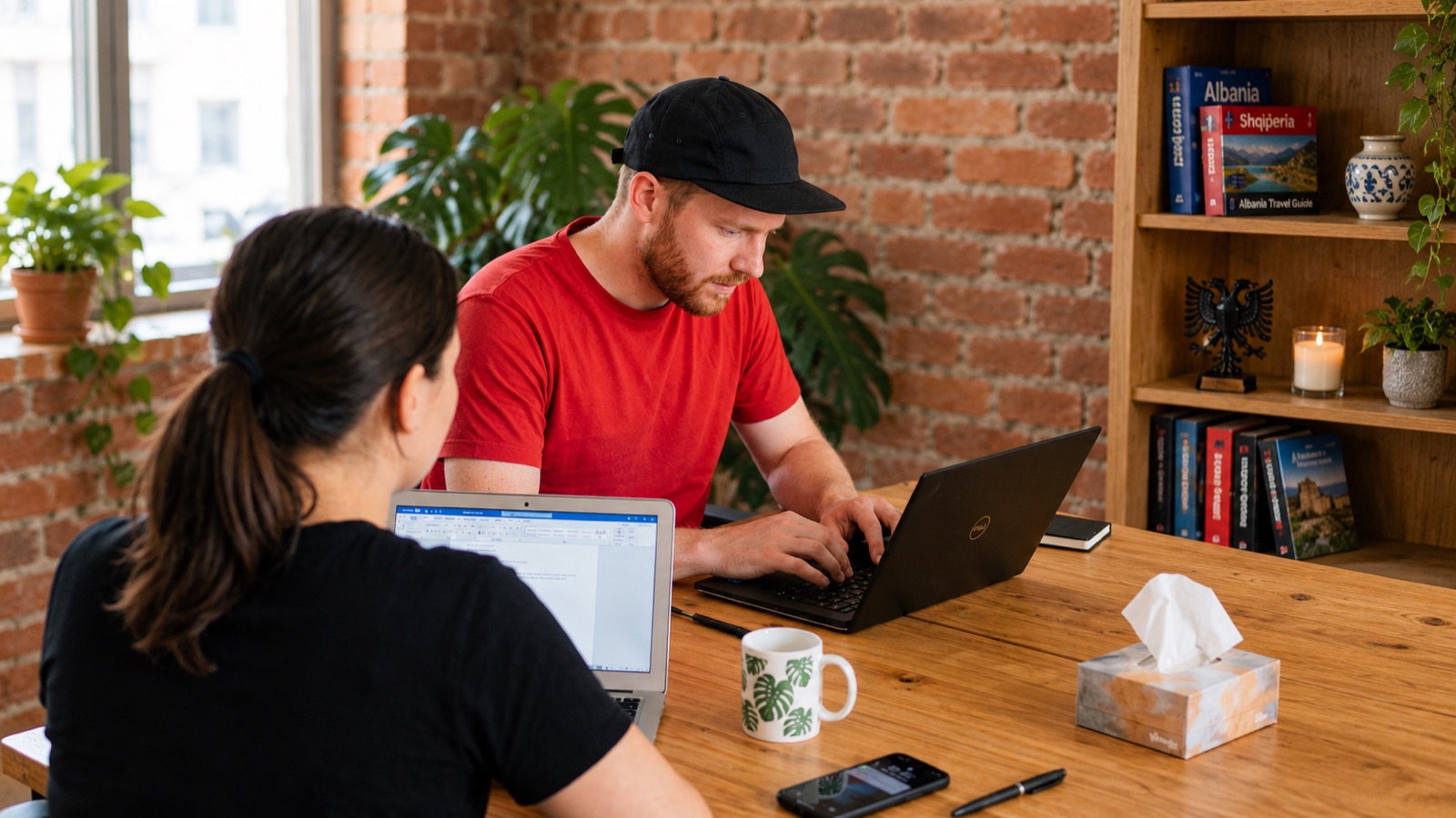 Two people working on laptops at a shared table in a coliving house in Albania